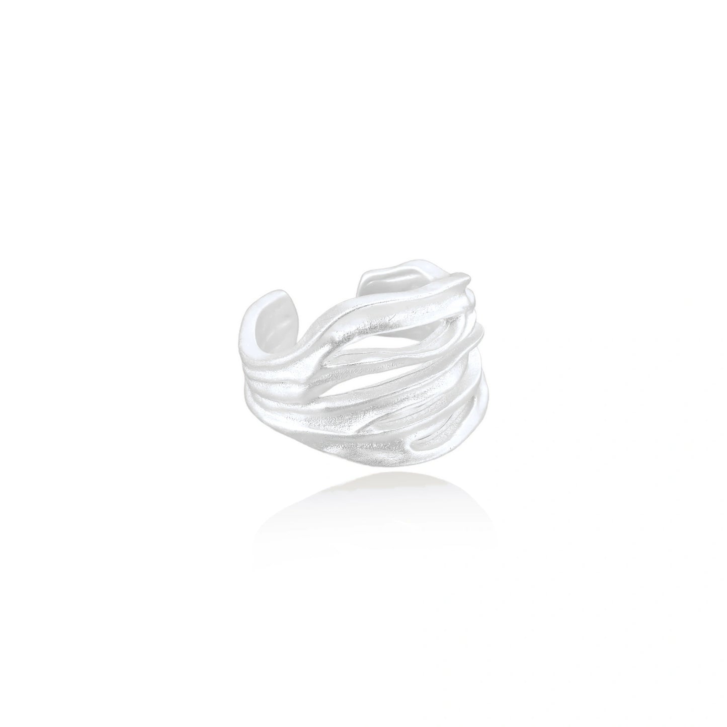 Wide sterling silver cuff ring with flowing wave patterns creating dimensional texture against cream background