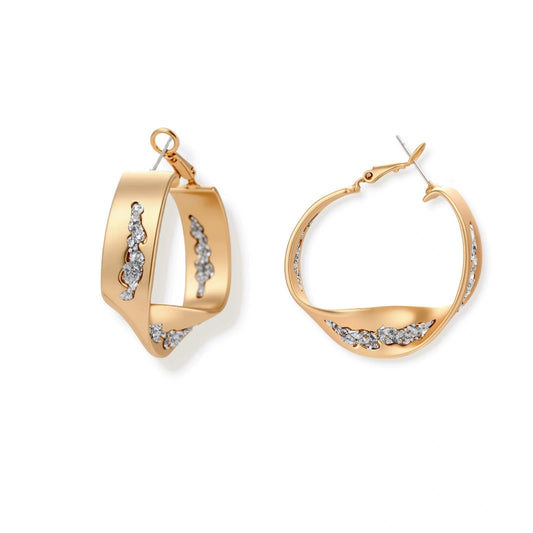 Organic-shaped gold hoop earrings with scattered crystals, featuring hinged closure on white background.