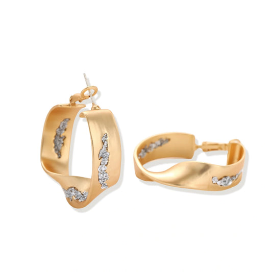 Organic-shaped gold hoop earrings with scattered crystals, featuring hinged closure on white background.